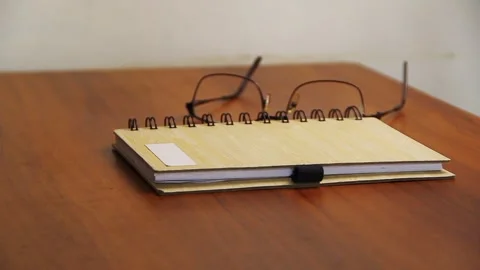Hand placing a notebook and writing materials on a wooden table. Stock Footage 337911470