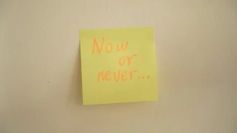 Hand Placing "now or never" Sticky Note on Wall Stock Footage 344514413