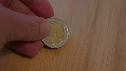 Hand placing number 2 euro coin on table Stock Footage 335457539