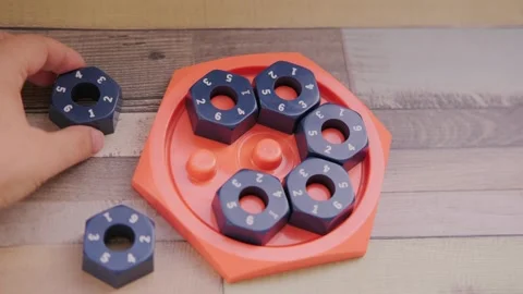 Hand placing numbered blue hexagonal puzzle pieces orange educational game .. Stock Footage 317699361