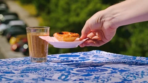 Hand placing one pastel de nata custard tart and picking white saucer with it 스톡 동영상 337723756