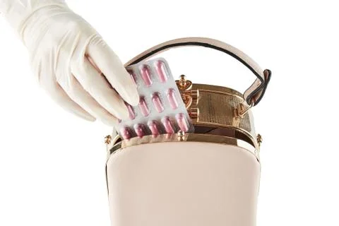 Hand placing package of pills in beige womans bag. Isolated Stock Photos