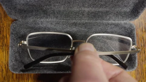 A hand placing a pair of glasses and lens cleaning cloth into a case. Video stock 295995483