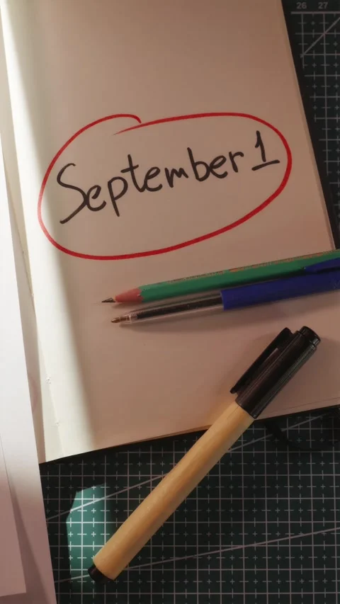 Hand placing pen and pencil next to 1 September note vertical Stock Footage 340139072