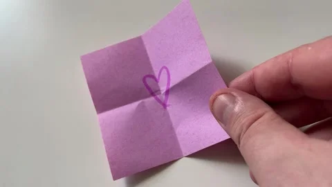 Hand Placing Pink Folded Note with Drawn Heart Symbol on White Surface 動画素材 340214527