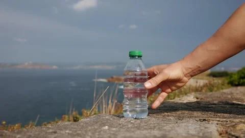 Hand placing a plastic water bottle. Eco-Friendly Plastic Bottle: Refreshing Stock Footage 245696128