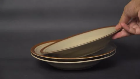 Hand Placing Plate on Stack of Dishes  Close-Up Kitchen Scene Stock Footage 331515101