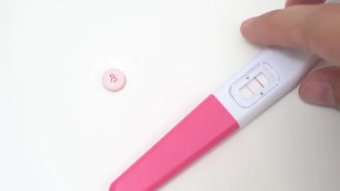 Hand Placing Positive Pregnancy Test Beside Pink Maternal Pill Stock Footage 340428313