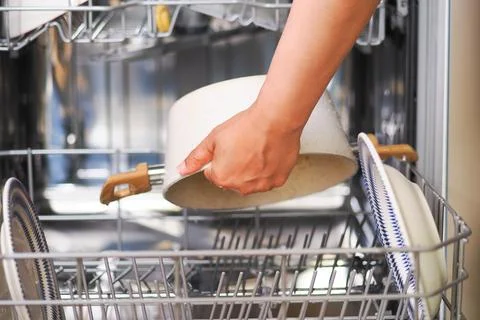 Hand placing a pot inside a dishwasher Stock Photos