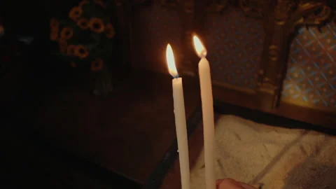 Hand placing a prayer candle into sand inside church as part of tradition Video stock 342112254