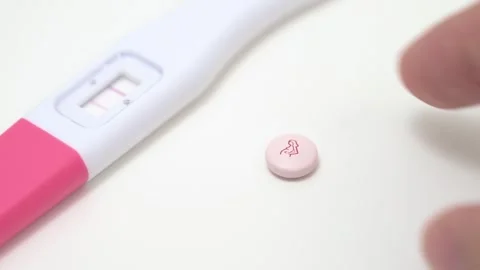 Hand Placing Prenatal Supplement Pill Next to Positive Pregnancy Test Stock Footage 340428341