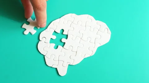 Hand Placing Puzzle Pieces into Brain Shape on Teal Background Stock Footage 295111917