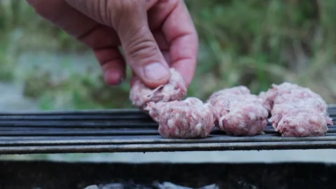 Hand placing raw minced meat sausages on hot grill Stock Footage 337982575