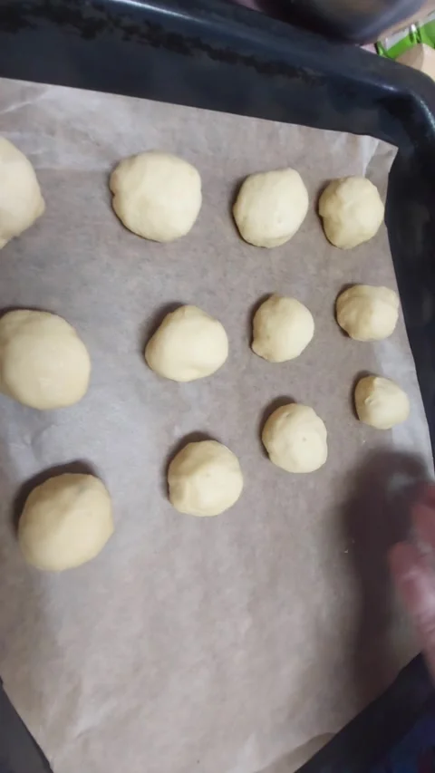 Hand Placing Raw Yeast Dough Balls on Baking Sheet with Parchment Paper Stock Footage 333642249