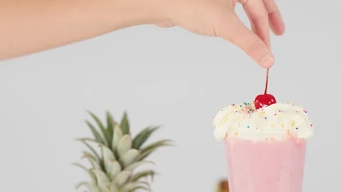 Hand Placing a Red Cherry on Whipped Cream Pink Smoothie 動画素材 326090488