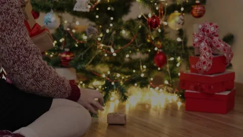Hand placing red craft gift boxes under decorated Christmas tree blinking lights Stock Footage 164857819