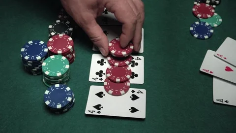 Hand placing red poker chips on playing cards showing pairs of fours and fives Stock Footage 337374556
