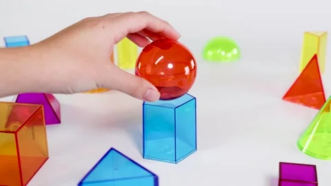 Hand Placing a Red Sphere on a Blue Hexagonal Prism Stock Footage 325177669