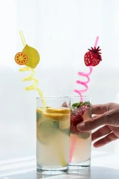 Hand placing refreshing lemonade and strawberry summer drinks Stock Photos