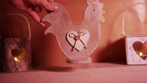 Hand Placing a Rustic Wooden Rooster Decoration with Heart Detail Stockbeeldmateriaal 338185942