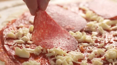 Hand Placing Salami On a raw pizza base with sauce and cheese. Stock Footage 270534696
