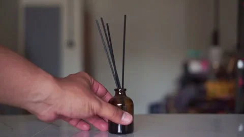 Hand placing scented reed diffuser on a marble countertop indoors. Stock Footage 346968737