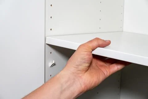 Hand placing shelf inside cabinet Stockfoto's