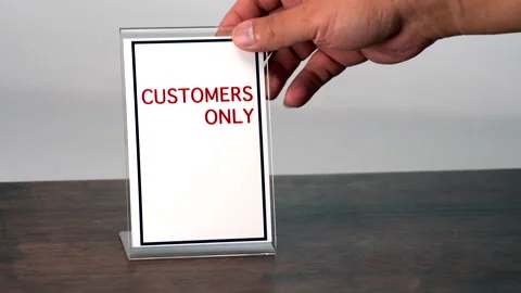 A hand is placing a sign for customers only on a wooden table. Stock Footage 314575569