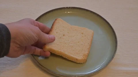 Hand Placing Slice of Bread on Plate, Minimal Food Concept Stock Footage 337014539
