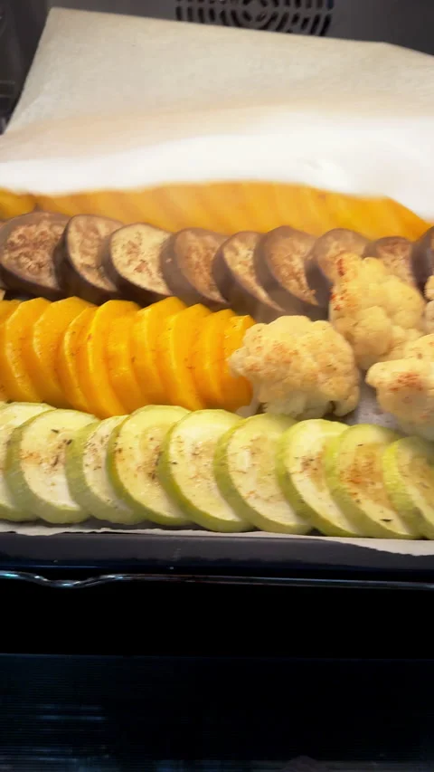 Hand placing sliced vegetables into the oven for baking Stock Footage 324534771