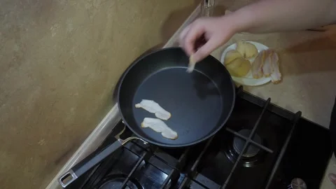 Hand placing slices of bacon into frying pan Vidéo 342363083