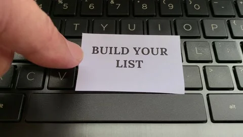 Hand placing small note pad with text build your list on laptop. Stock Footage 178745534