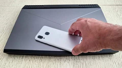 Hand Placing Smartphone on Laptop During Technology Demo Stock Footage 336708257