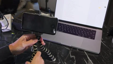 Hand placing smartphone on tabletop tripod, close-up of user setting up mobile Stock Footage 333650059