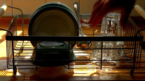Hand placing soapy glasses into a kitchen drainer / drying rack. Video stock 246877407