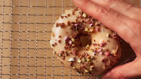 Hand Placing Sprinkle Donut on Metal Cooling Rack Stock Footage 331233241