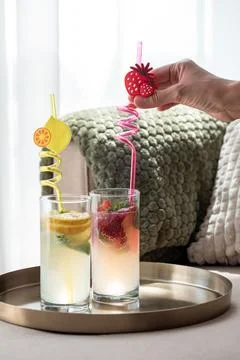 Hand placing strawberry straw in refreshing drink Stock Photos