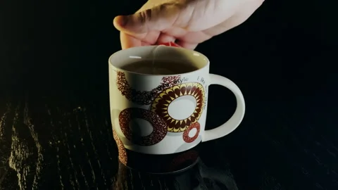 Hand placing a tea bag on a mug dark background 4k 60fps Stock Footage 255041357