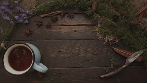 Hand Placing Tea on Rustic Table with Herbs, Spices and Pine Branches Stock Footage 289589998