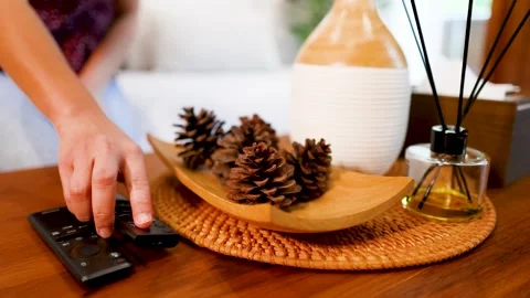 Hand Placing Television Remote Control on Wooden Coffee Table Surface Stock Footage 332978187