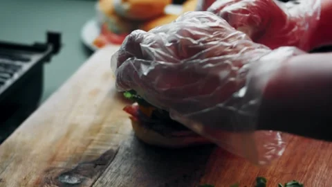 Hand placing a topping onto an open cheeseburger, 4K Stock Footage 341117525
