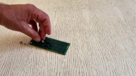 Hand Placing TV Remote Control Circuit Board on Wooden Table Surface Stock Footage 340746834