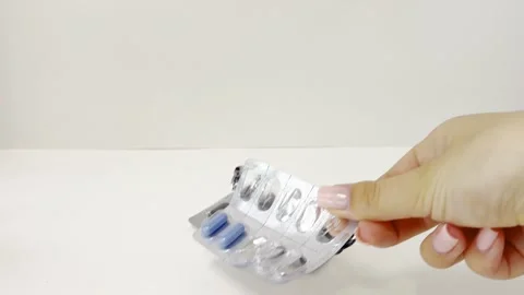 Hand placing various blister packs of pills, capsules, and lozenges on a wh.. Stock Footage 335141508