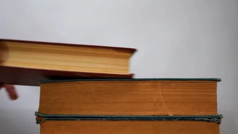 Hand placing a vintage book on a stack of old hardback books Stock Footage 346578366