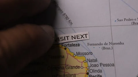 Hand placing Visit Next label on a map of Brazil for travel planning Stock Footage 346576303