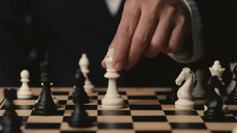Hand placing white chess king on a wooden board, business strategy concept Stock Footage 343428869