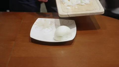 Hand placing white onion half on wooden cutting board at home kitchen table Video stock 323901817