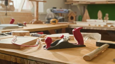 Hand Plane, Hammer and Carpentry Tools on Wooden Workbench in Sunlit Workshop Stock Footage 334409681