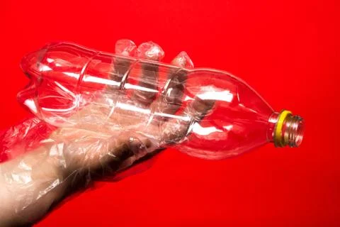 Hand in plastic or rubber disposable glove holds plastic transparent bottle o Stock Photos