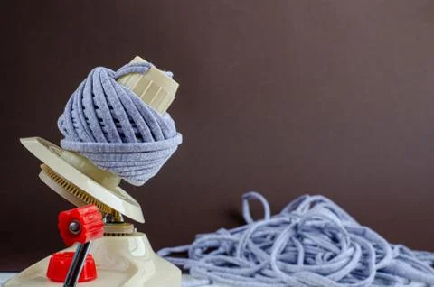 Hand plastic wool winder at work, gray yarn ball, brown background. prepair f Stock Photos